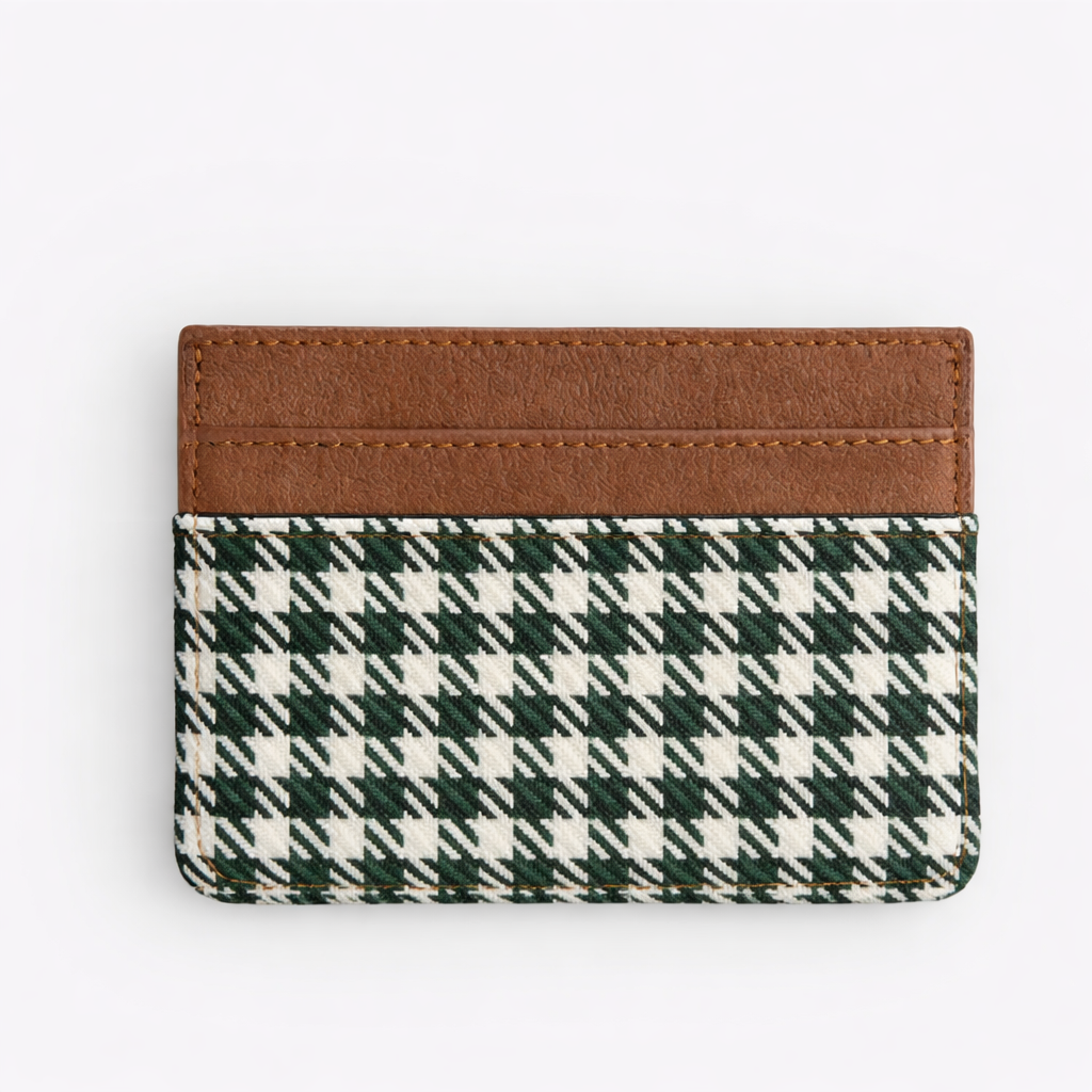Cardholder with green and white plaid design and brown leather strip on a white background