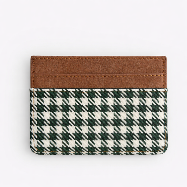Cardholder with green and white plaid design and brown leather strip on a white background